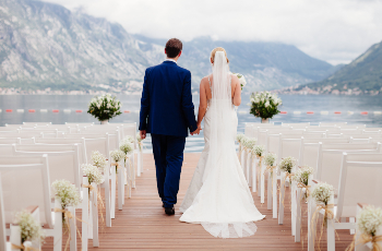 wedding couple at wedding ceremony back view. Mountains and sea background in Montenegro
